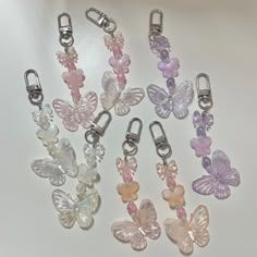 several different colored butterfly charms on a white surface with clippings attached to them