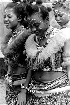 three women dressed in native garb standing next to each other with their hands on their hipss