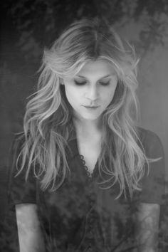 a black and white photo of a woman with long blonde hair looking down at her cell phone