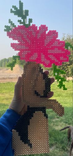 a person holding up a piece of art made out of plastic beads