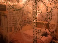 an unmade bed covered in white netting with lights strung from the ceiling above it