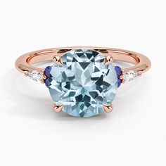 an oval blue topazte and diamond ring with rose gold accents on the band