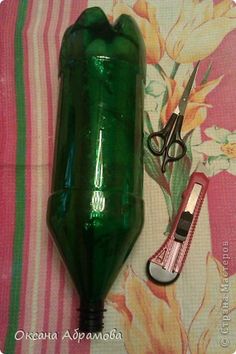 a green glass bottle sitting next to a pair of scissors