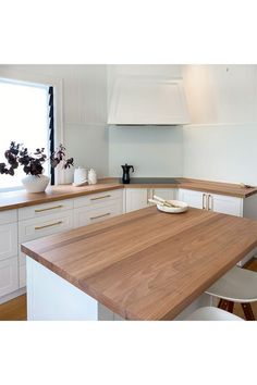 a kitchen with white cabinets and wooden counter tops, along with an island in the middle