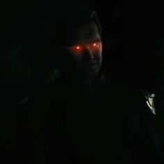 a man with glowing red eyes in the dark