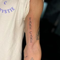 a man with a tattoo on his arm that says take care in cursive writing