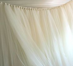 white tulle curtain with beads hanging from it's side in front of a window