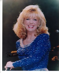 a woman with blonde hair holding a tennis racquet in her hand and smiling