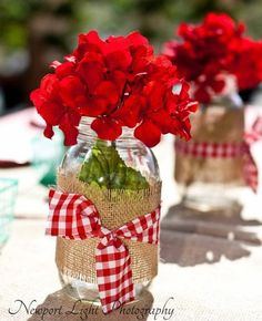 a cell phone with an image of red flowers in a mason jar on the screen