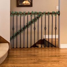 a stair rail with green vines on it in front of a framed picture and stairs