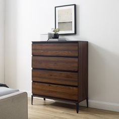 a wooden dresser sitting next to a bed in a bedroom on top of a hard wood floor