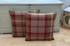 two brown and red plaid pillows sitting on the floor next to a white chest with a clock