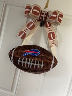 a door hanger with a football hanging from it's side and a bow on top