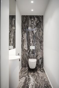 a white toilet sitting in a bathroom next to a wall mounted sink under a mirror