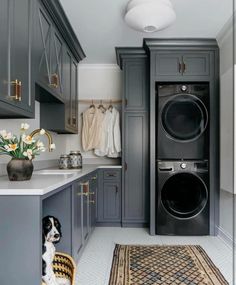 a washer and dryer are in the middle of a room with gray cabinets