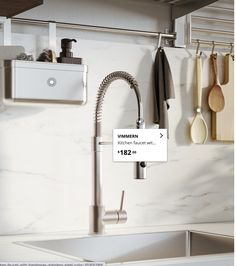 a kitchen sink with a faucet and some utensils hanging on the wall