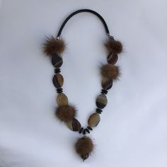 Winter necklace with a cuddly effect. Extravagant necklace made of valuable elements. Mink pom poms alternate with interesting brown-grained matt agates. In between there are elongated horn beads set in small silver discs. The suspension consists of a sturdy braided leather strap. The special feature of the pendant is a large faceted smoky quartz. An extremely distinctive necklace made of harmonizing materials. An eye-catcher. Particularly good to wear on knits. Closure: carabiner. Length: 72 cm Extravagant Necklace, Winter Necklace, Mink Fur, Braided Leather, Smoky Quartz, Pom Poms, Favorite Jewelry, Charm Necklace, Leather Straps