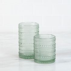 two green glass tumblers sitting next to each other on a white counter top,