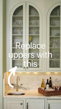 a kitchen with white cabinets and wine glasses on the counter top, along with two bottles of wine