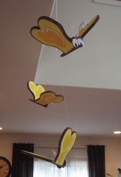 some yellow and brown decorations hanging from the ceiling in a living room with two clocks