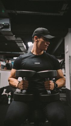 a man sitting on top of a bench holding two dumbbells in his hands