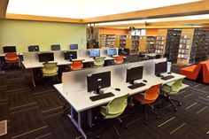 an empty library with rows of computers and orange chairs