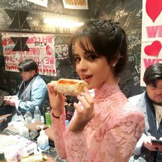 a woman in a pink dress eating a slice of pizza