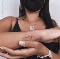 a woman wearing a face mask and holding her arm with the word love tattooed on it