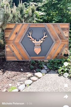 a deer head mounted to the side of a wooden sign in front of some trees