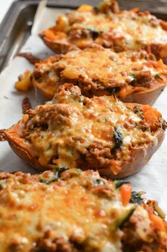 several stuffed sweet potatoes with meat and cheese on top are lined up in a row