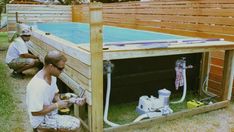 two men working on an above ground pool in the back yard with wood fence around it