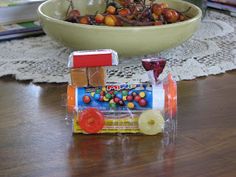 a toy train sitting on top of a wooden table next to a bowl of fruit