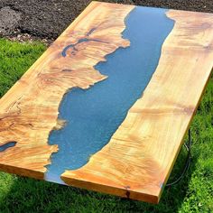 a table made out of wood with blue water in the center and green grass around it