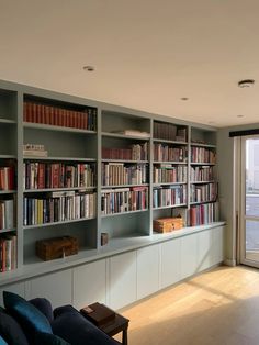 a living room filled with lots of books and furniture next to a sliding glass door