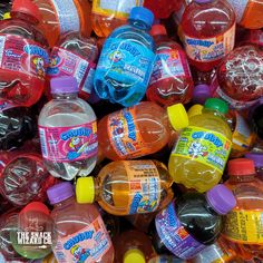 a pile of plastic bottles filled with different colored liquids and colors on top of each other