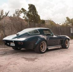 a black car parked on top of a dirt road