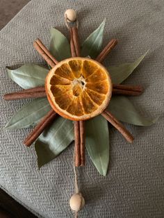 an orange cut in half sitting on top of a cushion with cinnamon sticks and leaves