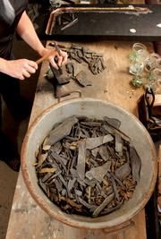 a woman is working with wood shavings in a bowl on a wooden table