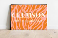 an orange and pink zebra print with the name clemson south carolina on it in front of a white wall