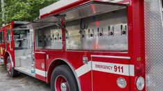 a red fire truck parked next to a forest