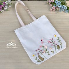 a white bag with embroidered flowers on it