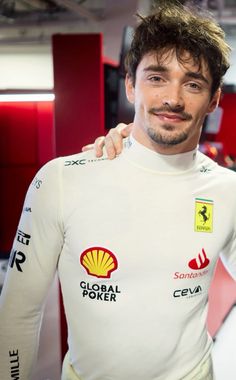 two men standing next to each other in front of red and white walls with logos on them