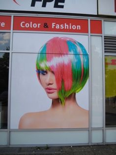 a large advertisement on the side of a building with colorful hair and bright colors in it