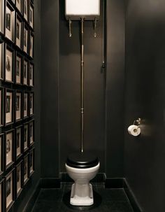 a bathroom with black walls and pictures on the wall