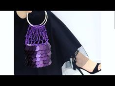 a woman's handbag with purple and black beads hanging from the front, next to her legs