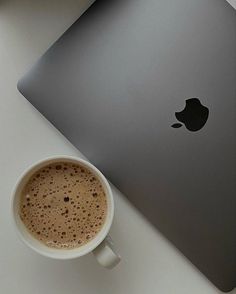 a cup of coffee next to an apple laptop