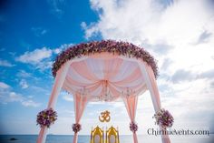 an outdoor wedding setup on the beach with pink and white draping over it