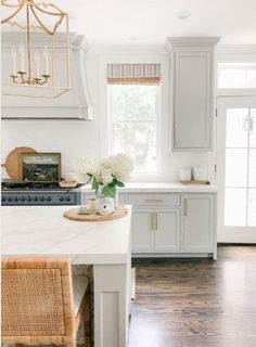 a kitchen with white cabinets and wood floors is pictured in this image, there are flowers on the counter