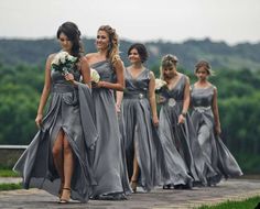 the bridesmaids are walking down the path in their gray dresses and bouquets