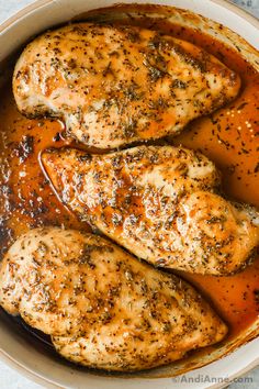 two pieces of chicken in a sauce in a white bowl on top of a table